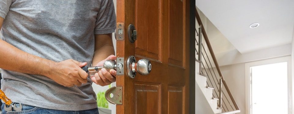serrurier changeant une serrure sur une porte en bois