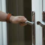Closeup shot of a person holding a door knob and opening the door