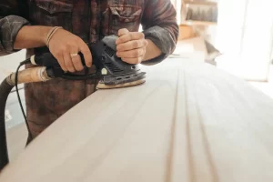 Conclusion d'un projet entre un artisan et son client dans un atelier de bois, avec un ordinateur affichant les services menuiserie à Lille pour une gestion de projet moderne et transparente.