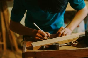 Artisan menuisier travaillant avec précision sur l'assemblage d'un cadre en bois dans son atelier, illustrant la qualité des services menuiserie à Lille pour vos projets sur mesure.