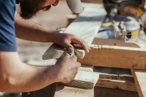 Menuisier professionnel vérifiant les plans d'un escalier en bois sur une tablette numérique, démontrant l'expertise et le suivi technique des services menuiserie à Lille.
