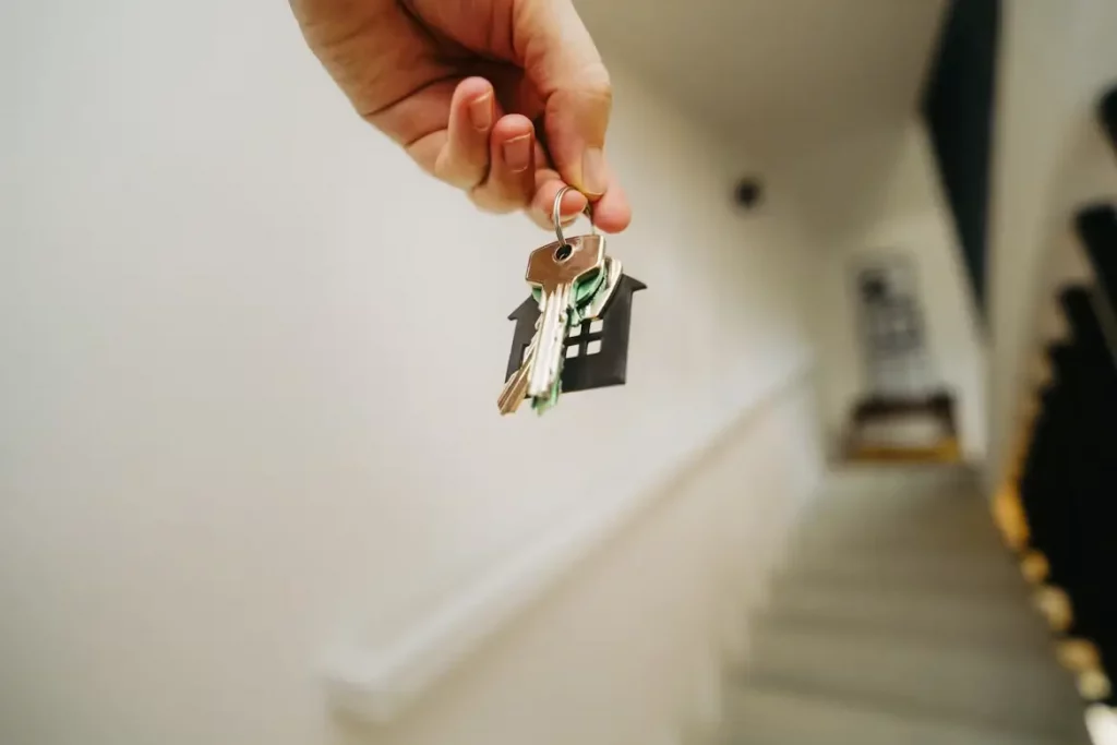 Main tenant des clés d'appartement dans une cage d'escalier — porte claquée clé à l'intérieur.